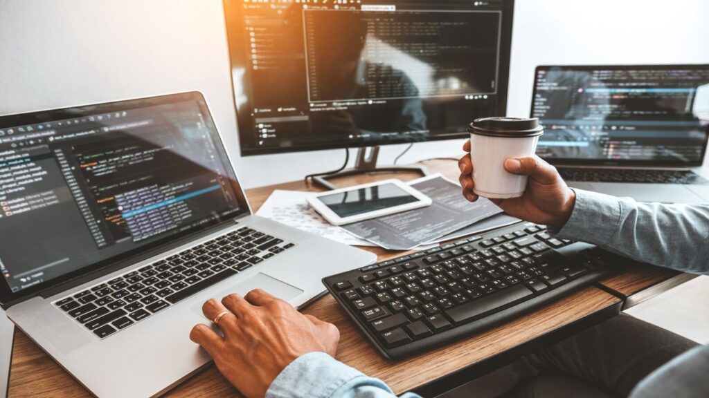 Hands at a keyboard with numerous monitors in view.